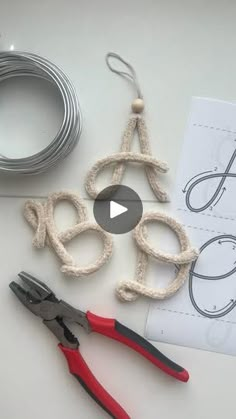 crochet letters and scissors on a table with paper, wire, and thread