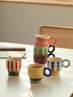 four coffee cups sitting on top of a white table