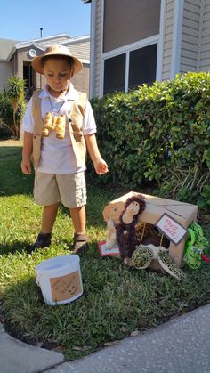 a little boy that is standing in the grass with some stuff on his feet and wearing a hat