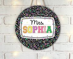 a sign that says mrs sophha hanging on a brick wall with lights around it