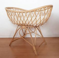 a wicker chair sitting on top of a hard wood floor next to a white wall