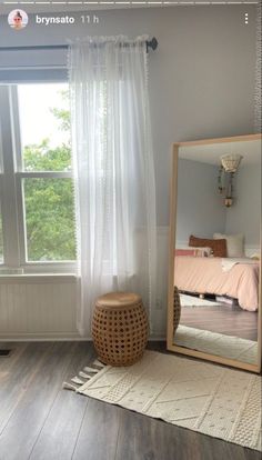 a mirror sitting on top of a hard wood floor next to a rug and window