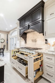 an open drawer in the middle of a kitchen with black cabinets and white counter tops