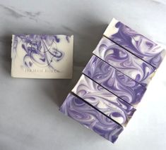 three bars of soap sitting next to each other on a white counter top with purple swirls