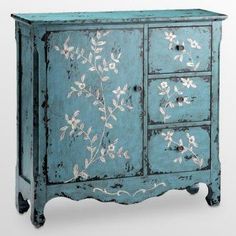 an old blue cabinet with flowers painted on the doors and drawers is shown against a white background