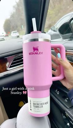 a person holding a pink coffee cup in their car