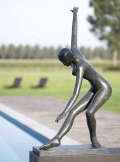 a statue of a woman reaching up into the air with her arm outstretched in front of a swimming pool