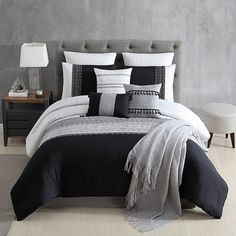 a bed with black and white comforters in a room next to a night stand