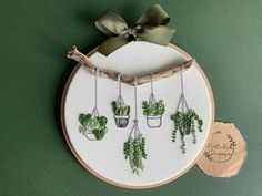 a cross stitch pattern with potted plants hanging from it's sides on a wooden hoop