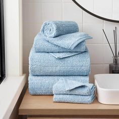 a stack of blue towels sitting on top of a wooden counter next to a mirror