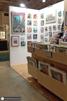 a display case filled with magazines on top of a wooden table next to a white wall