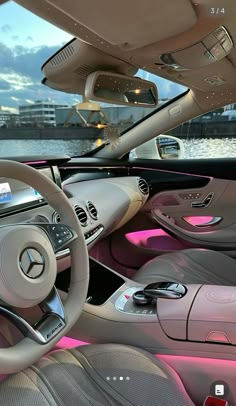 the interior of a car with pink lights and steering wheel, along with other vehicles