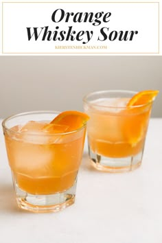 two glasses filled with orange whiskey sourer and garnished with an orange slice