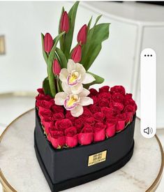 a heart shaped box filled with red roses and white orchids on top of a table