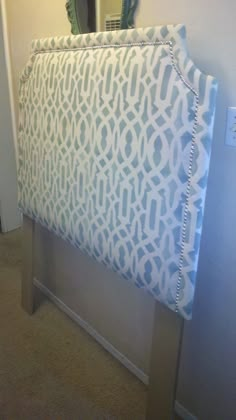 an upholstered headboard with blue and white designs on it in a bedroom