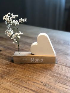 a small vase with flowers in it sitting on a wooden table next to a sign that says best mama