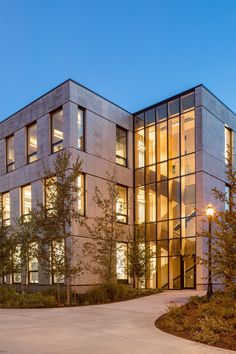 a large building with lots of windows and trees in front of it at night time