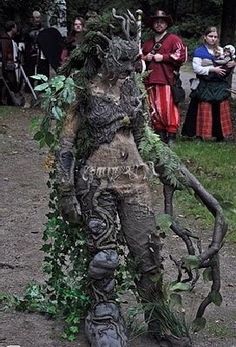 a man dressed up as a creature standing in the dirt