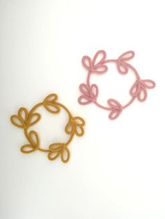 two crochet designs on a white surface, one is pink and the other is gold