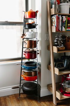 a shelf with pots and pans on it next to a window