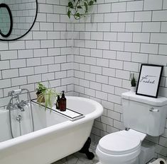 a white bath tub sitting next to a toilet in a bathroom under a round mirror