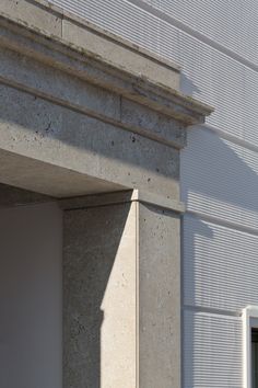 the corner of a white building with a clock on it's face and window sill