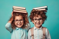 two young children wearing glasses and holding books on their heads while standing next to each other