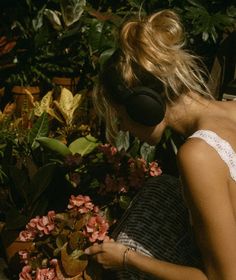 a woman sitting in front of flowers looking at her cell phone