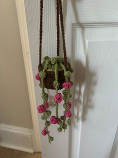 a crocheted bag hanging from a hook on a door handle with flowers attached to it