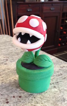 a toy mushroom sitting on top of a green potted plant with its mouth open