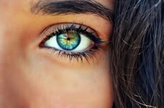 a woman's eye with long hair and green eyeshade, close up