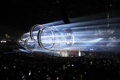 the stage is lit up with white lights and people are standing on it in front of them