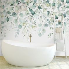 a white bath tub sitting next to a wall covered in green leafy leaves on it's side