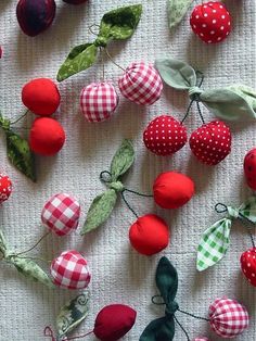 an arrangement of fabric cherries and leaves on a white table cloth background with red, green, and blue gingham checkered fabrics