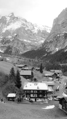 a black and white photo of a town with mountains in the background