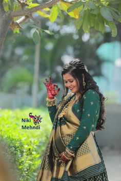 a woman in a green and gold sari holding her hand up