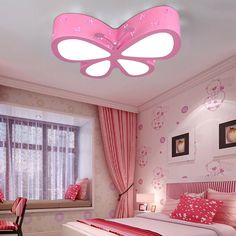 a bedroom with pink and white decor, including a ceiling light in the shape of a butterfly