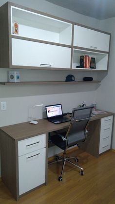 an office desk with a laptop computer on top of it and cabinets above the desk