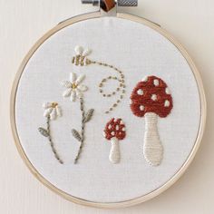 a cross stitch project with mushrooms and daisies