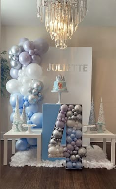 a table topped with balloons and a number four sign in front of a chandelier