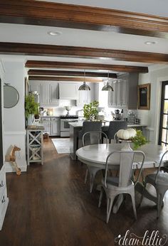 the kitchen and dining room are all white with wood trim on the ceiling, along with hardwood flooring