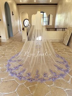 a wedding veil with purple flowers on the bottom is hanging in front of a doorway