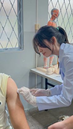 two women in white lab coats and gloves are working on clay sculptures with mannequins behind them