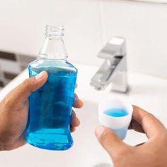 a person holding a blue bottle in front of a sink