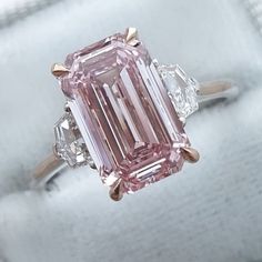 a pink diamond ring with three diamonds on it