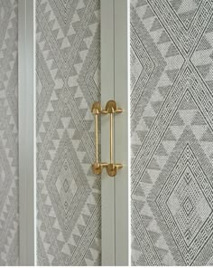 the door handles are gold in color on this white and gray wallpapered room