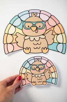 a person holding up two stickers with an owl on them