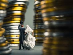 a bride and groom figurine standing in front of stacks of gold coins on the floor