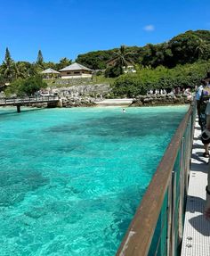 people standing on a pier looking out at the blue water in front of some houses