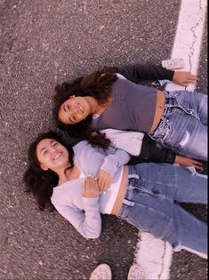 two young women standing next to each other on the street with their arms around each other